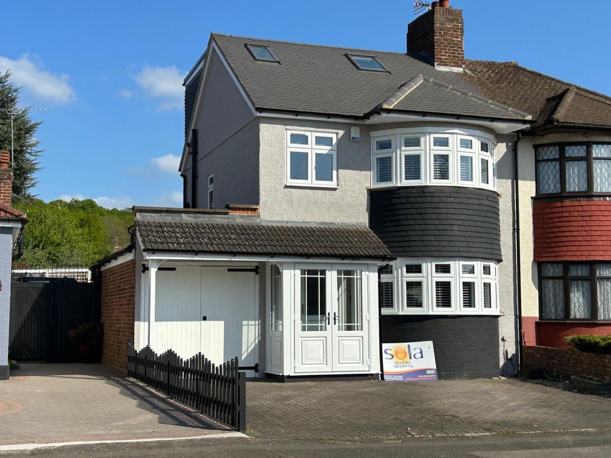 Sola installation with white bay windows and entrance doors on a semi-detached home